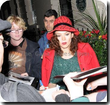 Anna Friel outside the Theatre Royal Haymarket, where she stars in 'Breakfast At Tiffany's wearing a red hat and matching red coat with a green sequined dressLondon. England