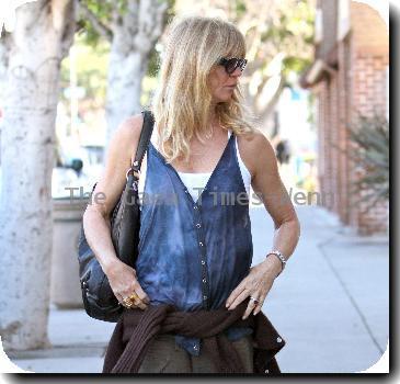 Goldie Hawn wearing baggy trousers and an oversized waistcoat together with a cardigan tied around her waist, pays a parking meter with a credit card on her way to a pharmacy in Santa Monica..