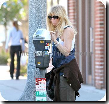 Goldie Hawn wearing baggy trousers and an oversized waistcoat together with a cardigan tied around her waist, pays a parking meter with a credit card on her way to a pharmacy in Santa Monica..