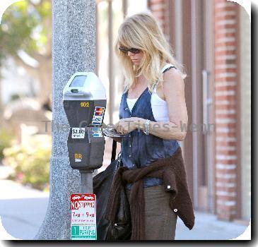 Goldie Hawn wearing baggy trousers and an oversized waistcoat together with a cardigan tied around her waist, pays a parking meter with a credit card on her way to a pharmacy in Santa Monica..