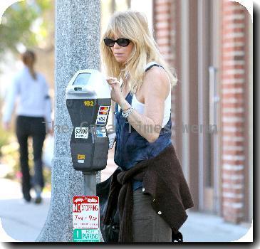 Goldie Hawn wearing baggy trousers and an oversized waistcoat together with a cardigan tied around her waist, pays a parking meter with a credit card on her way to a pharmacy in Santa Monica..