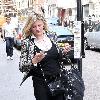 Susannah Constantine text messaging on her mobile phone as she strolls around central London. London.