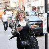 Susannah Constantine text messaging on her mobile phone as she strolls around central London. London.