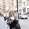 Susannah Constantine text messaging on her mobile phone as she strolls around central London. London.