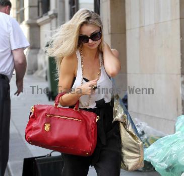 Emma Rigby cant resist letting down her long blonde hair, when she spots our photographer, as she strolls through central London, carrying two large handbags. London.