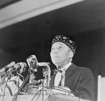 Elijah Muhammad standing behind microphones at podium