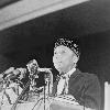 Elijah Muhammad standing behind microphones at podium