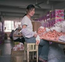 Un operaia guarda il fotografo mentre monta una partita di bambolotti  L unica differenza apparente rispetto alle fabbriche italiane � l ingegnosa combinazione degli sgabelli  che