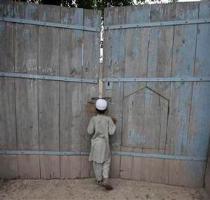 <p>A boy looks through the main gate of the ancestral home of the family of Faisal Shahzad  a Pakistani American held in New York on suspicion of driving a bomb laden car into Times Square  in Mohib Banda  in Pakistan  north western Khyber Pakhtoonkhwa province  May 5  2010  < p>